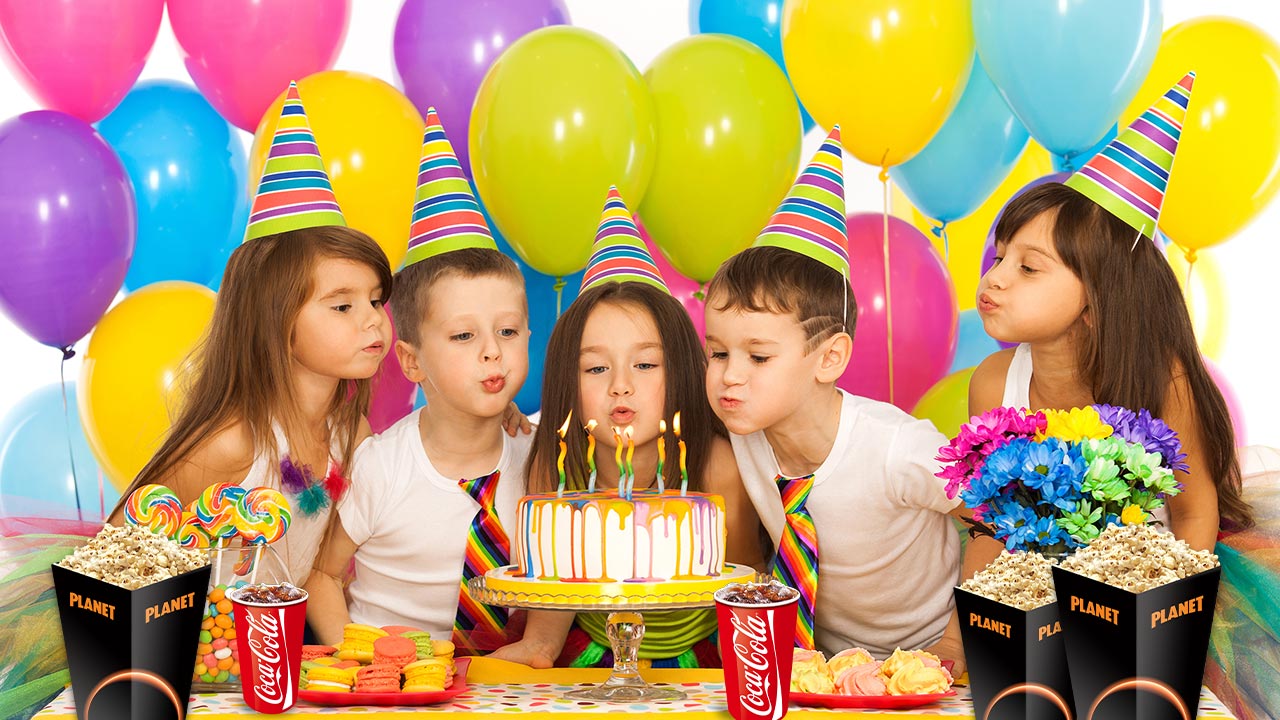 ילדים עם כובעי מסיבה ובלונים מכבים נרות על העוגה